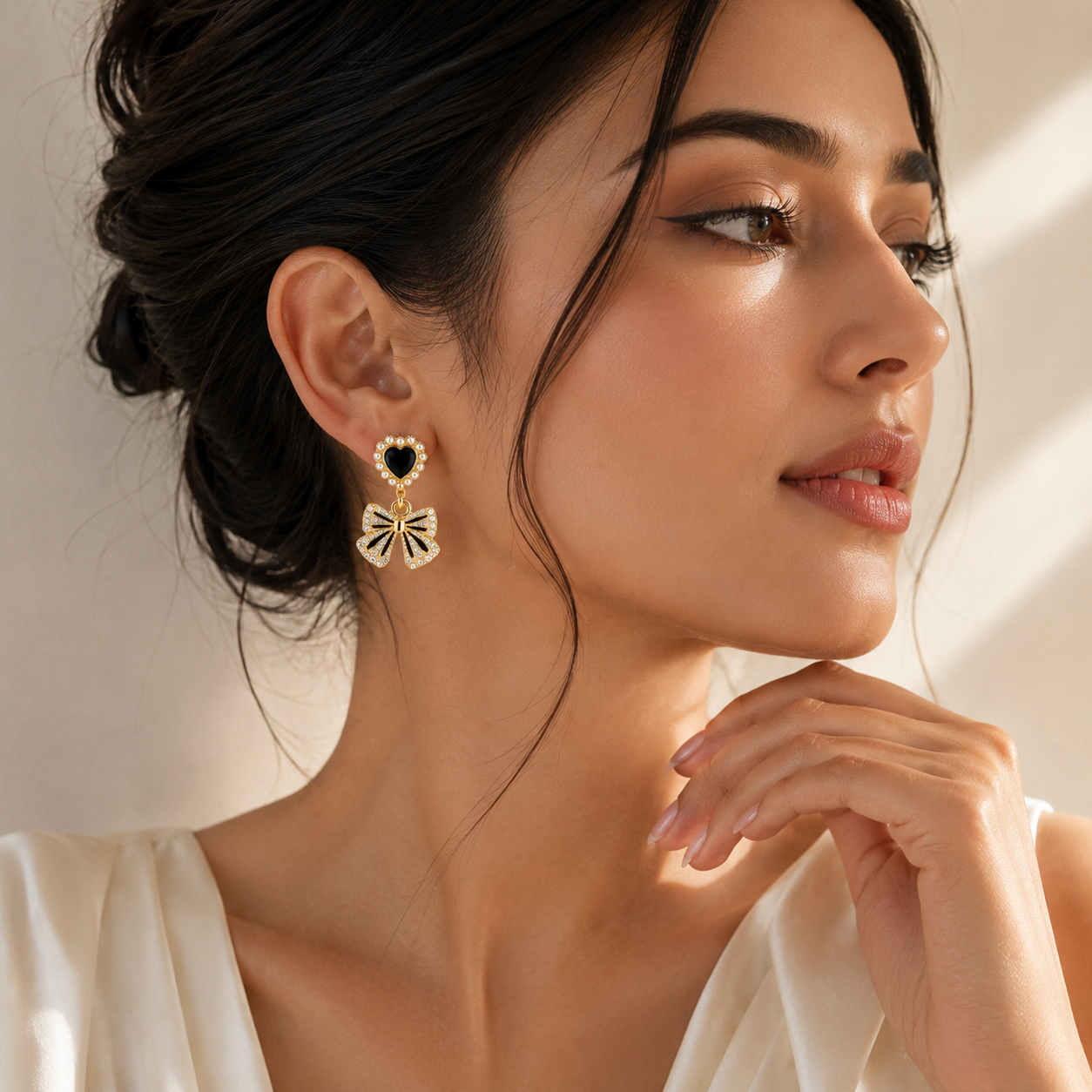 Elegant gold drop earrings with black heart and bow design, perfect for everyday luxury style