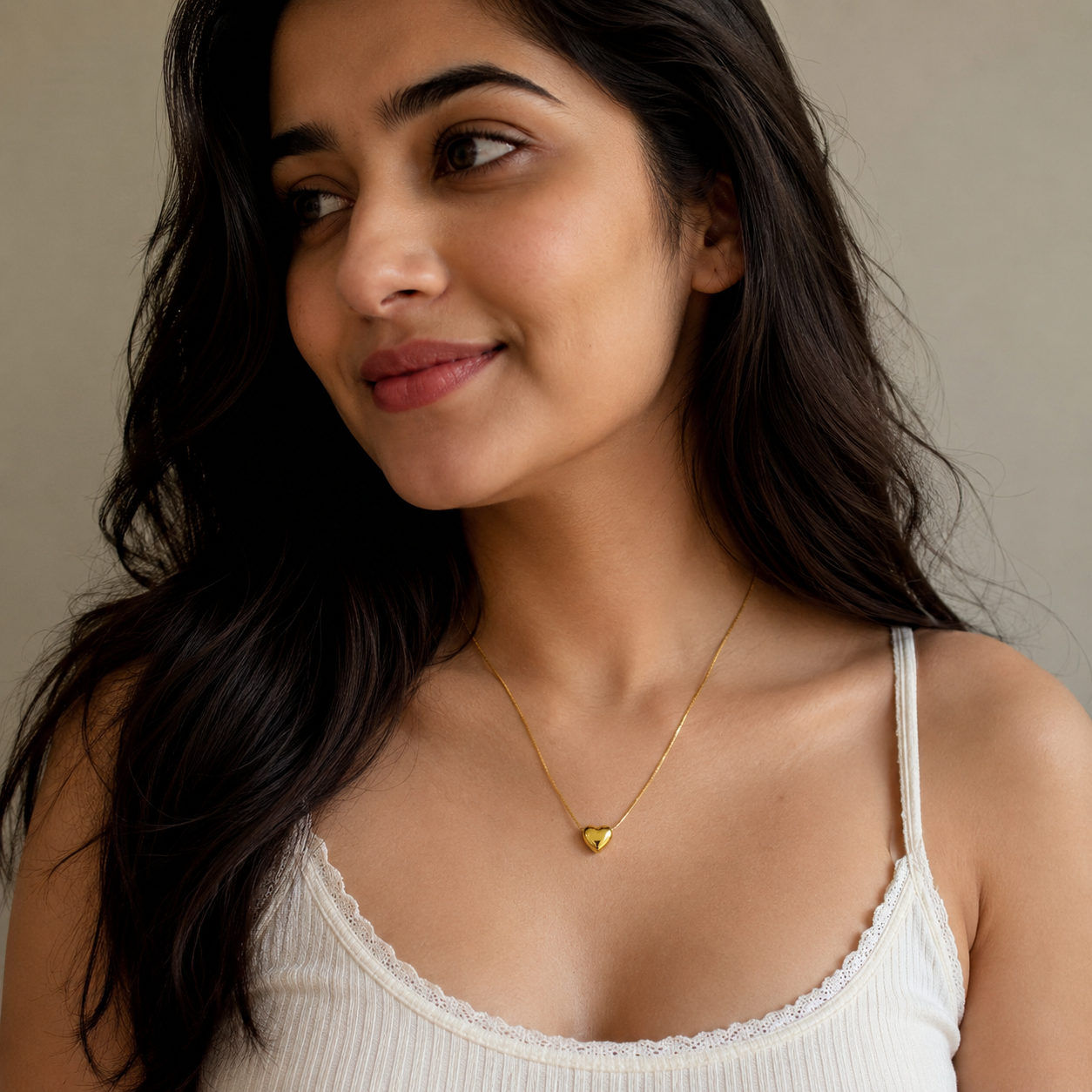 Woman wearing delicate gold heart necklace, anti-tarnish everyday luxury jewelry for women