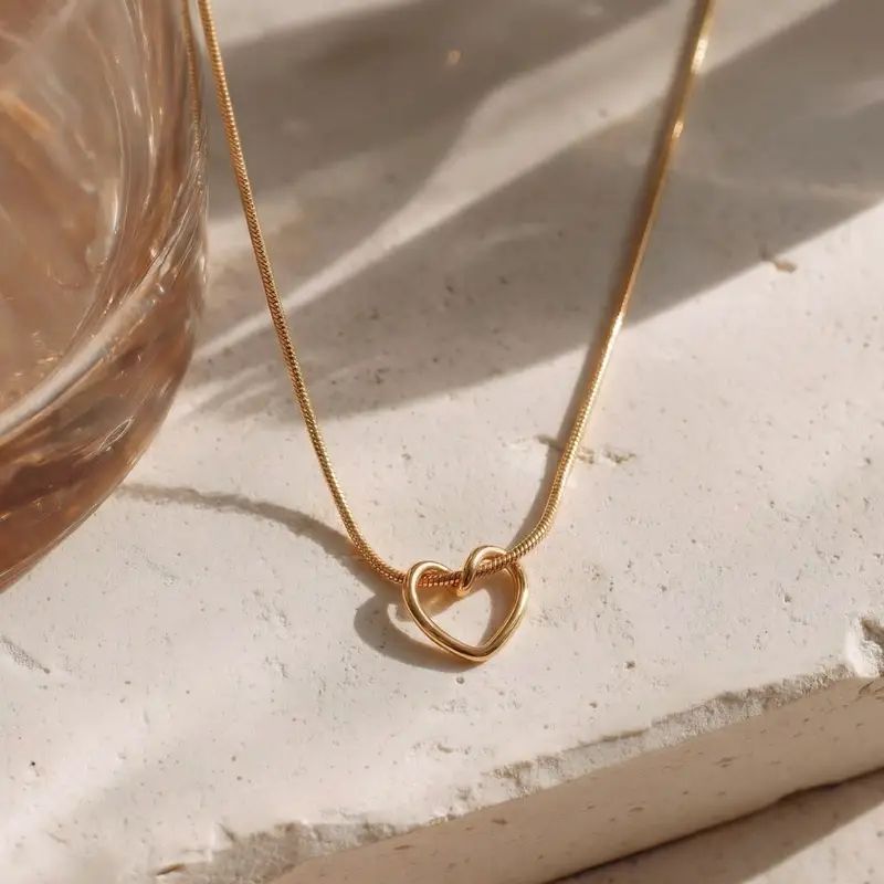 Gold heart pendant necklace on textured stone, elegant everyday luxury jewelry for women