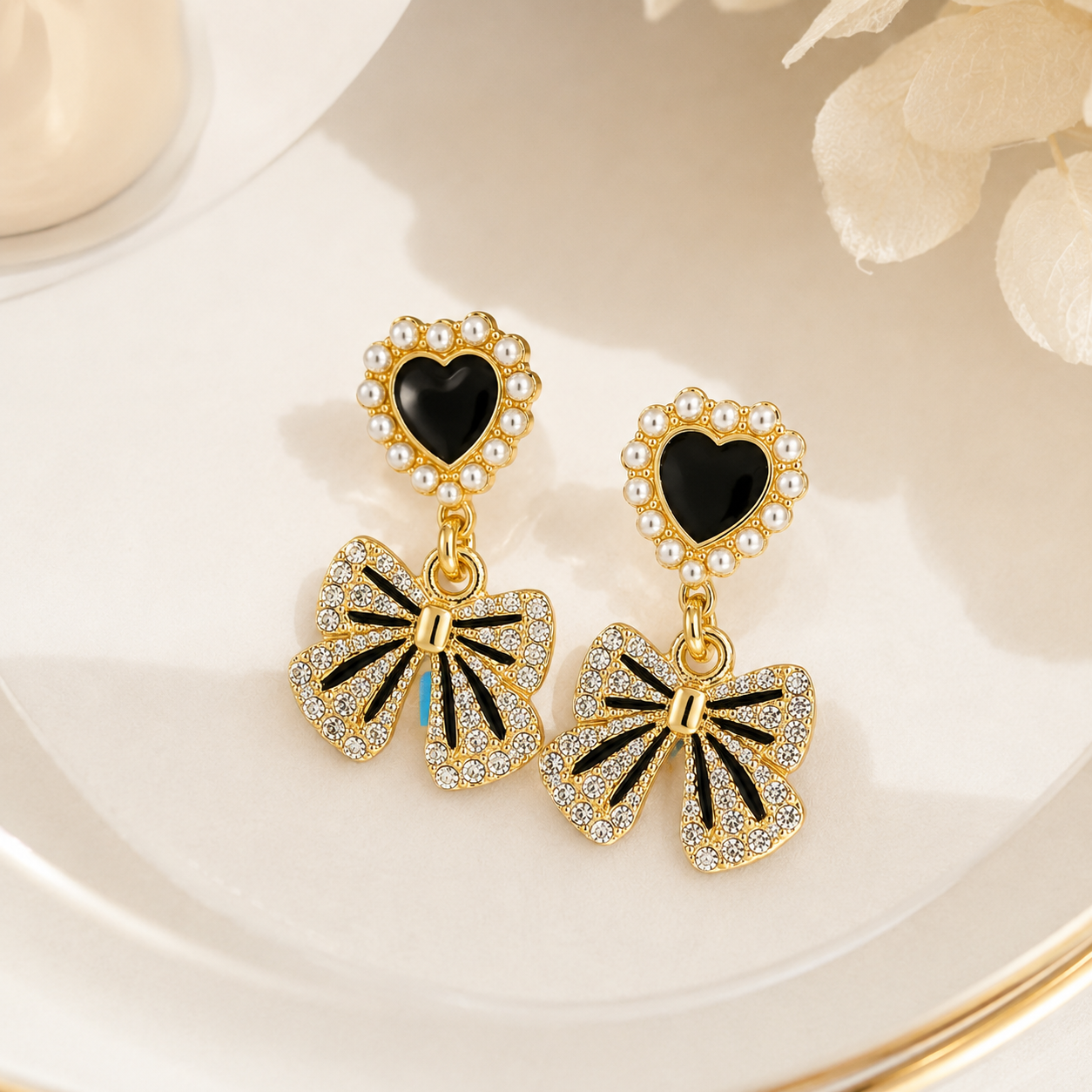 Gold heart drop earrings with black enamel and crystal bow charms, elegant anti-tarnish jewelry for women