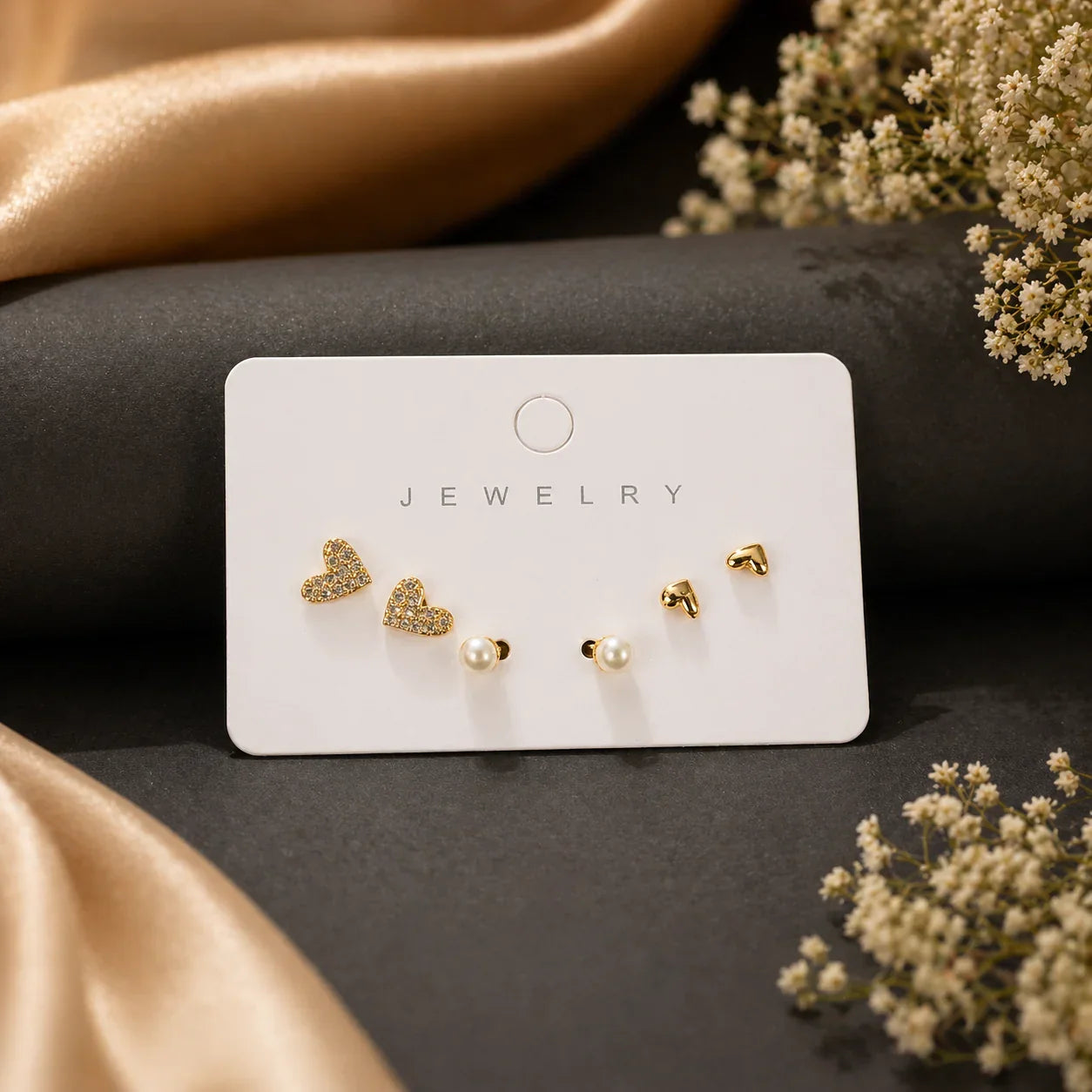 Gold heart and pearl stud earrings on jewelry card, elegant everyday luxury for women