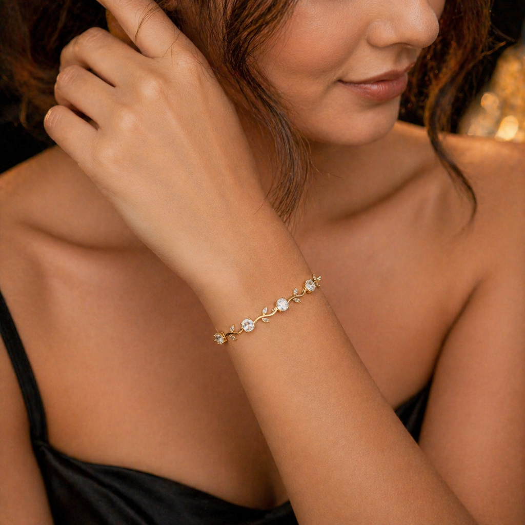 Elegant gold bracelet with clear stones and leaf details, worn on woman's wrist for everyday luxury style.