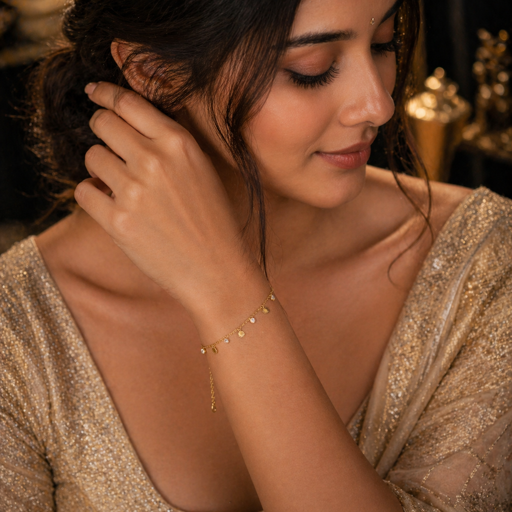 Delicate gold bracelet with sun charms and dangling chain, worn by woman in shimmering gold attire
