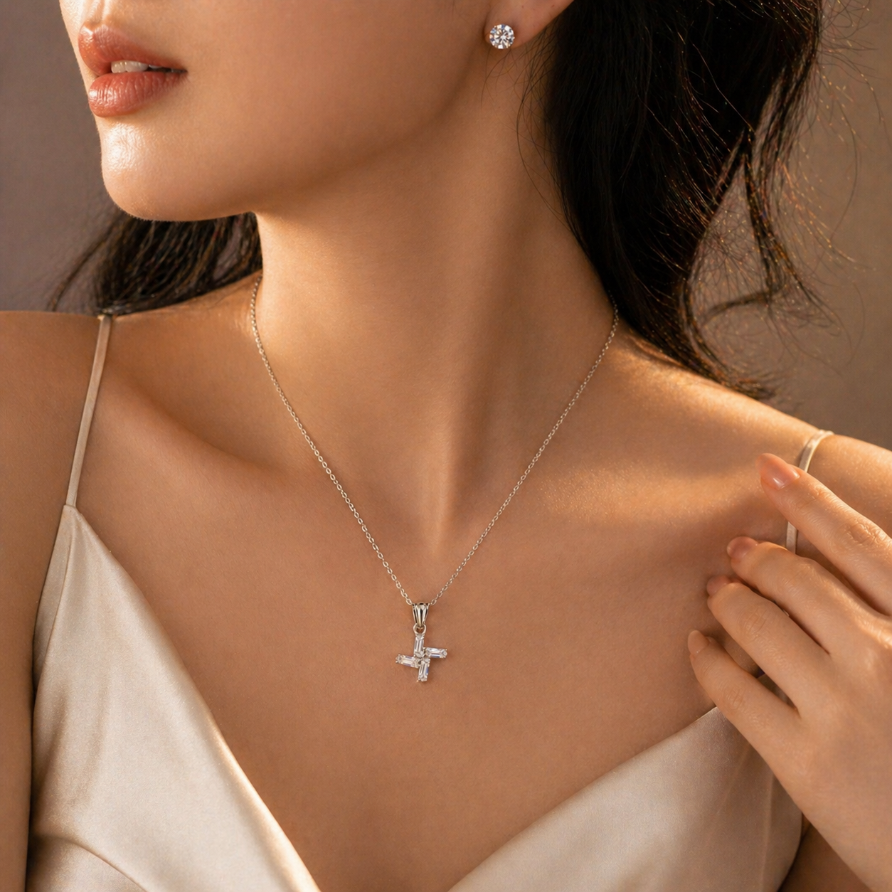 Elegant cross pendant necklace with sparkling stones, paired with stud earrings for everyday luxury.